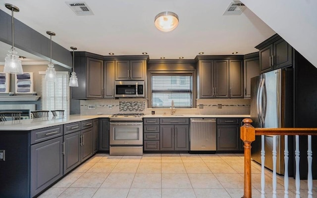 kitchen featuring visible vents, a peninsula, stainless steel appliances, light countertops, and a sink