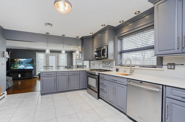 kitchen with visible vents, appliances with stainless steel finishes, a peninsula, gray cabinets, and a sink