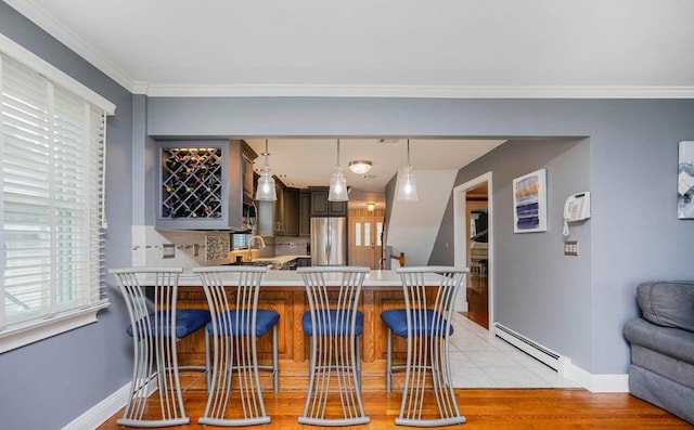 kitchen featuring a baseboard heating unit, a peninsula, light countertops, ornamental molding, and stainless steel refrigerator