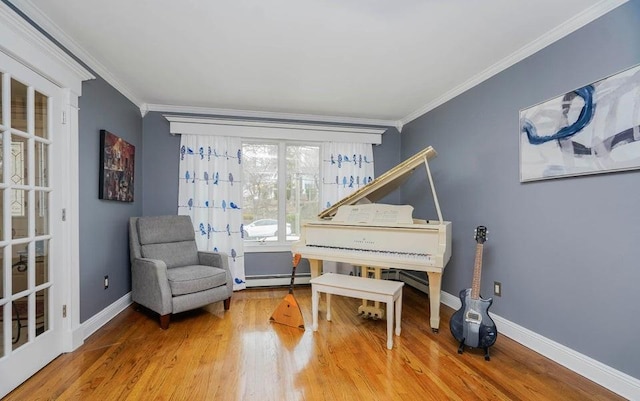 living area with a baseboard heating unit, baseboards, wood finished floors, and crown molding