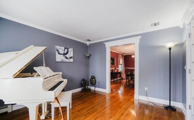 home office featuring baseboards, visible vents, wood finished floors, and ornamental molding