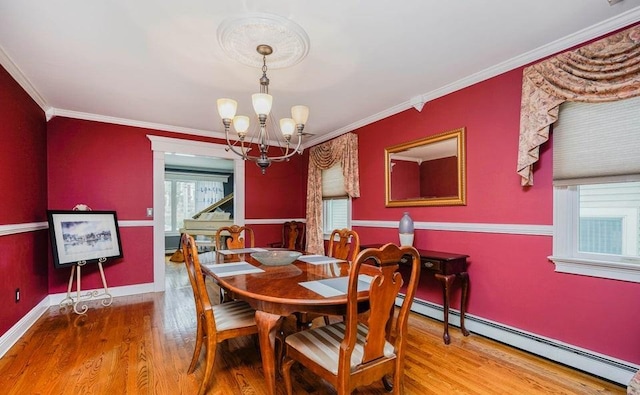 dining area with a chandelier, ornamental molding, baseboard heating, and wood finished floors