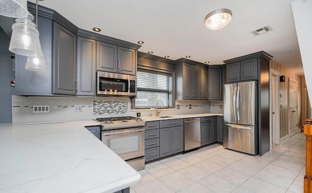 kitchen with pendant lighting, light tile patterned floors, stainless steel appliances, backsplash, and a sink