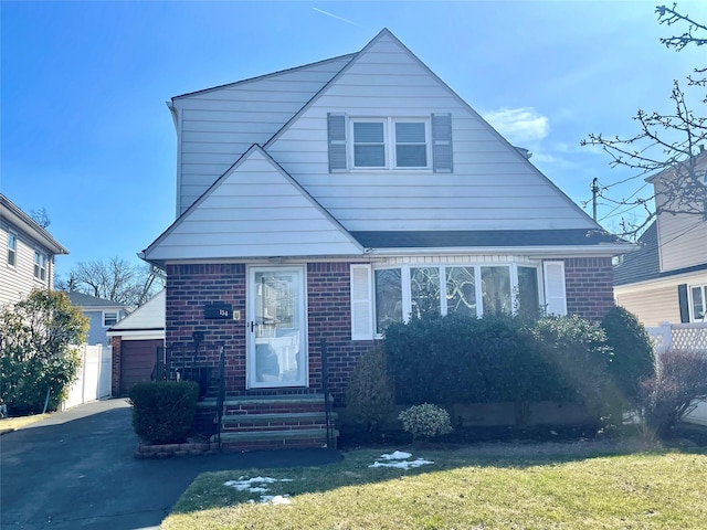 bungalow-style home with entry steps, a front yard, and brick siding