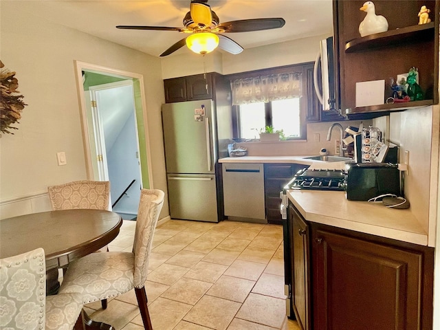 kitchen with dark brown cabinetry, appliances with stainless steel finishes, light countertops, open shelves, and a sink