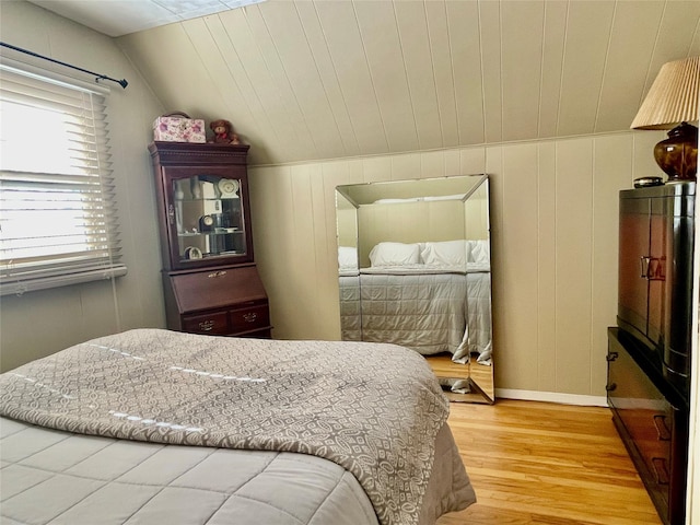 bedroom featuring vaulted ceiling, light wood finished floors, and baseboards