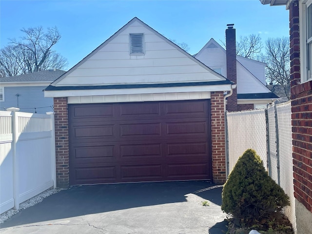 garage featuring fence and aphalt driveway