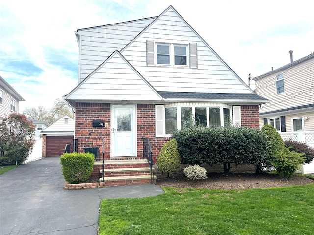 bungalow-style house with brick siding, an outbuilding, a detached garage, and a front yard