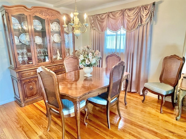 dining area featuring ornamental molding, light wood finished floors, and a notable chandelier