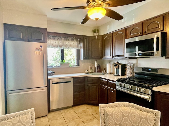 kitchen with a sink, light tile patterned floors, ceiling fan, light countertops, and appliances with stainless steel finishes