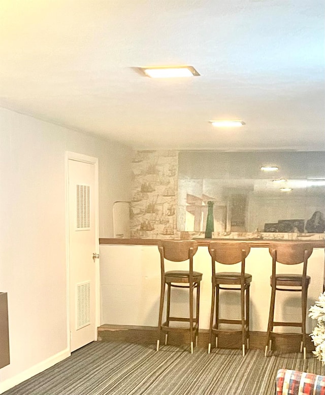 bar featuring indoor bar, baseboards, visible vents, and carpet floors