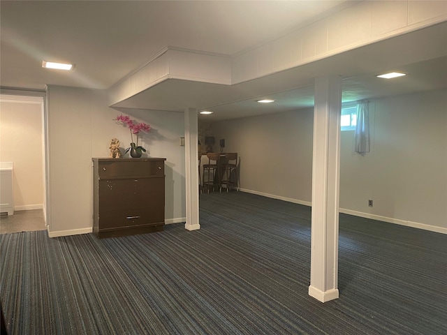 below grade area with dark carpet and baseboards
