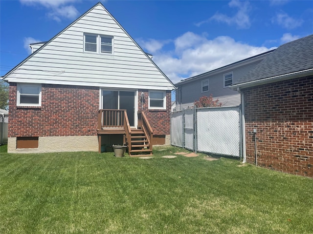 rear view of property with fence, a yard, and brick siding