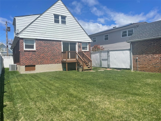 rear view of house with a gate, brick siding, fence, cooling unit, and a lawn