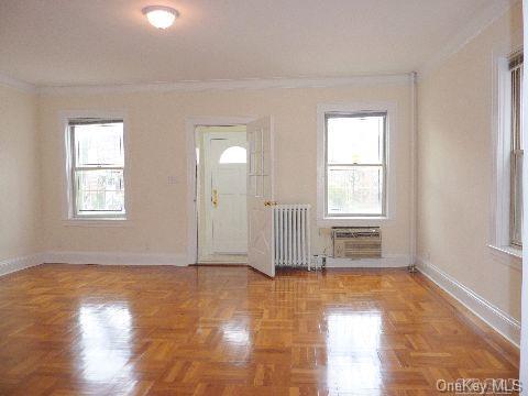 entrance foyer featuring ornamental molding, radiator, an AC wall unit, and baseboards