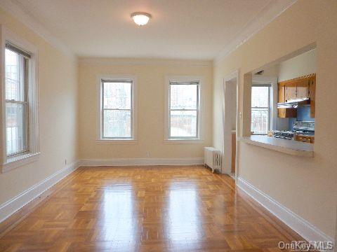 unfurnished room featuring baseboards, crown molding, and radiator heating unit