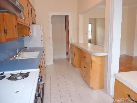 kitchen with under cabinet range hood, light countertops, a sink, and range with gas stovetop