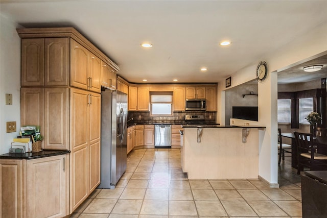 kitchen featuring a breakfast bar area, light tile patterned floors, a peninsula, stainless steel appliances, and tasteful backsplash