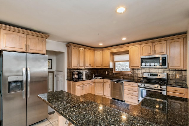 kitchen with light brown cabinetry, decorative backsplash, appliances with stainless steel finishes, and dark stone counters