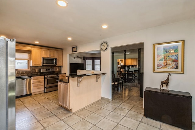 kitchen featuring tasteful backsplash, stainless steel appliances, a kitchen bar, and light tile patterned flooring