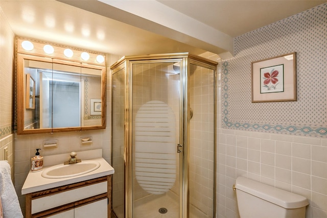 full bathroom featuring toilet, tile walls, a shower stall, wallpapered walls, and vanity