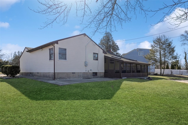 rear view of property with crawl space, a patio area, a lawn, and a sunroom