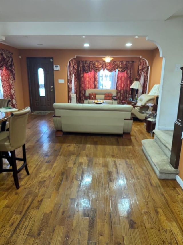 living area featuring a wealth of natural light, arched walkways, and hardwood / wood-style flooring