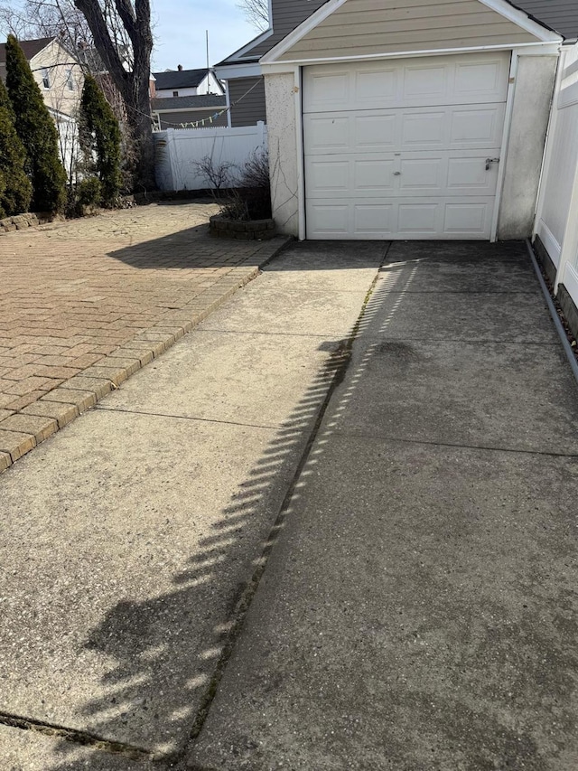 garage featuring fence and driveway