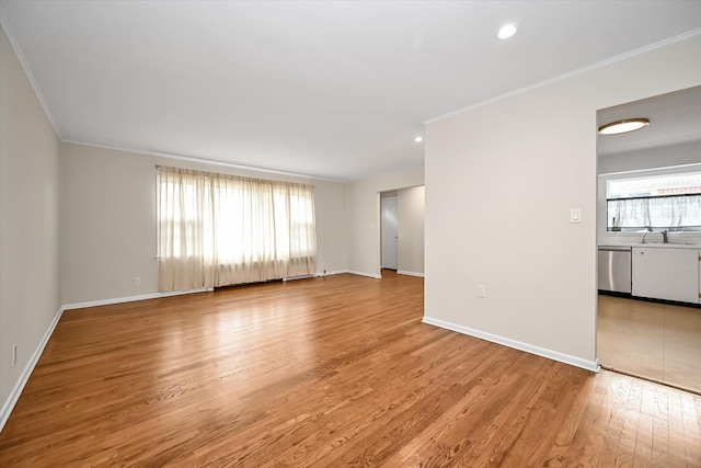 unfurnished living room featuring ornamental molding, a sink, recessed lighting, light wood-style floors, and baseboards