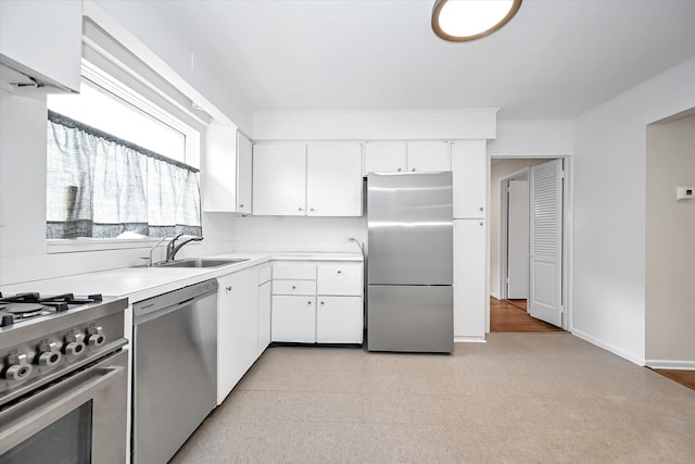 kitchen featuring a sink, stainless steel appliances, white cabinets, light countertops, and baseboards