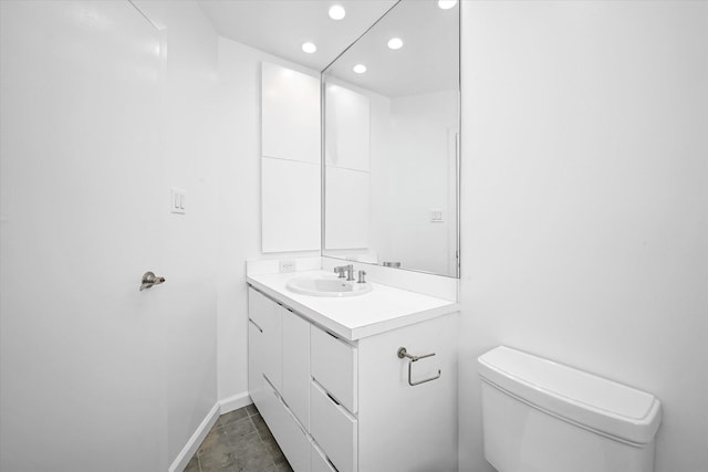 bathroom featuring vanity, toilet, recessed lighting, and baseboards