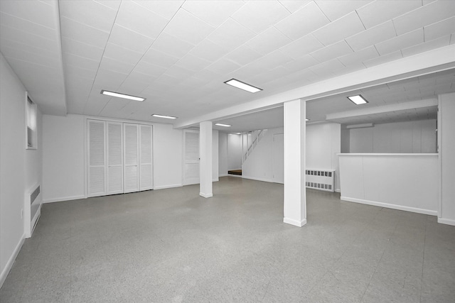 finished basement featuring stairway, radiator, and baseboards