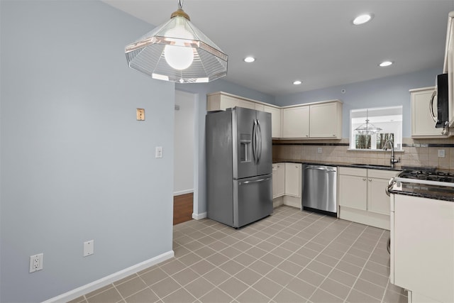 kitchen with baseboards, a sink, appliances with stainless steel finishes, pendant lighting, and tasteful backsplash