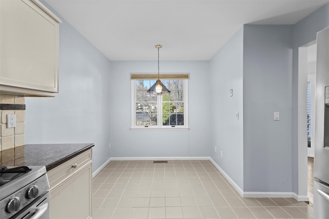 unfurnished dining area featuring light tile patterned flooring and baseboards