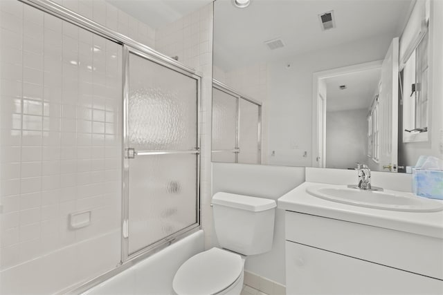 bathroom featuring vanity, toilet, combined bath / shower with glass door, and visible vents