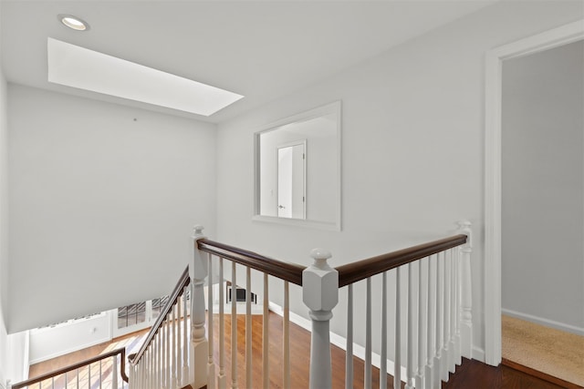 stairway featuring baseboards, wood finished floors, and a skylight