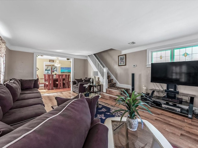 living room featuring stairs, visible vents, and wood finished floors