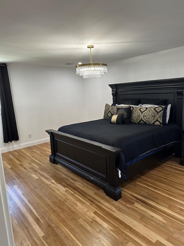 bedroom featuring visible vents, baseboards, and wood finished floors