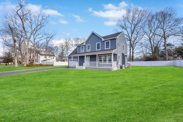 view of front of property featuring a front lawn, covered porch, driveway, and fence