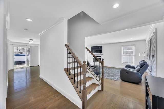 staircase featuring baseboards, a healthy amount of sunlight, wood finished floors, and crown molding