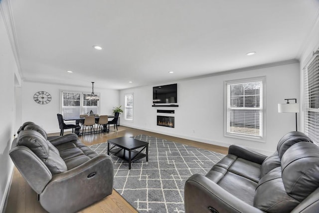 living area with crown molding, baseboards, dark wood finished floors, recessed lighting, and a glass covered fireplace