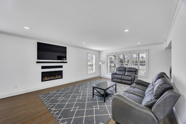 living area featuring wood finished floors, baseboards, recessed lighting, a warm lit fireplace, and ornamental molding