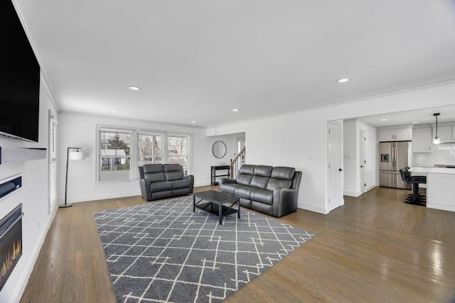 living room featuring baseboards, a warm lit fireplace, dark wood finished floors, and crown molding