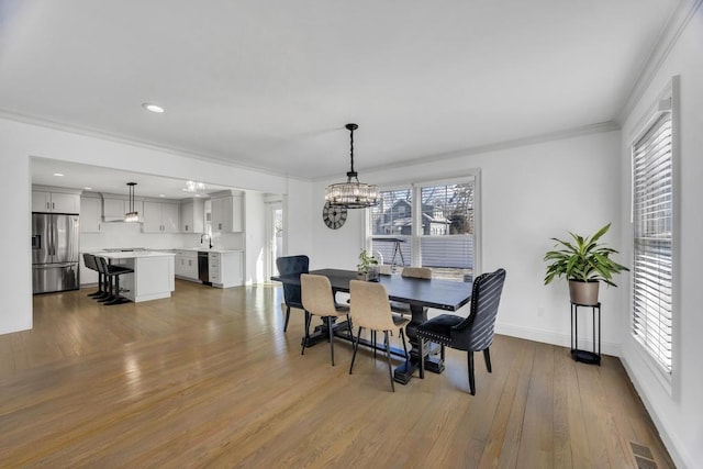 dining space featuring visible vents, baseboards, ornamental molding, wood finished floors, and a notable chandelier