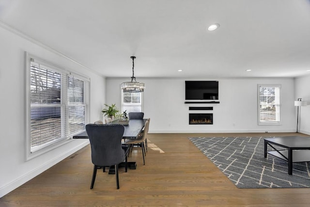 dining room featuring a lit fireplace, ornamental molding, and dark wood-style flooring