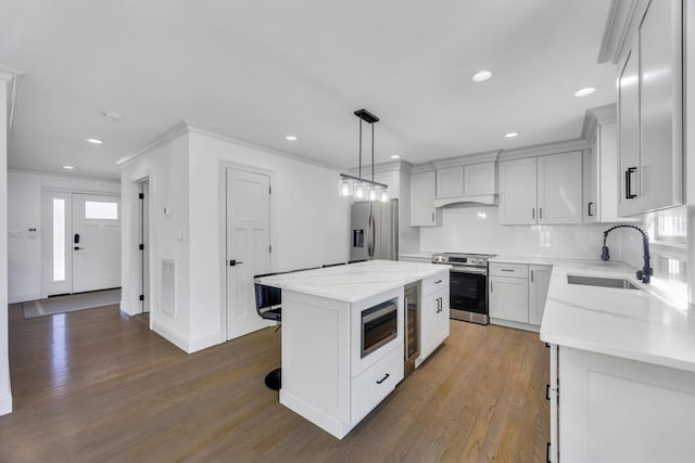 kitchen with a sink, backsplash, a center island, stainless steel appliances, and light wood-style floors