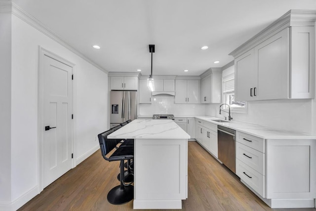 kitchen with a breakfast bar, wood finished floors, stainless steel appliances, and a sink