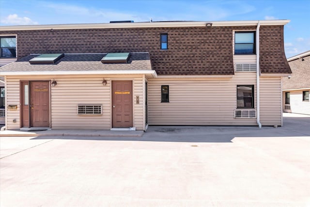 view of property with a patio area, concrete driveway, and a shingled roof