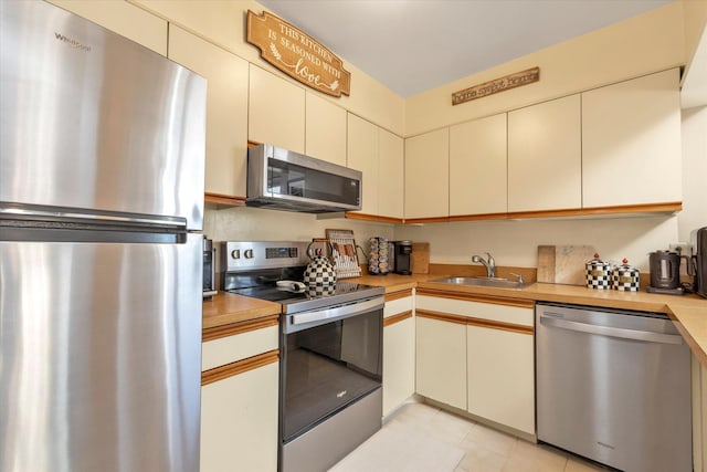 kitchen featuring light countertops, cream cabinets, appliances with stainless steel finishes, and a sink