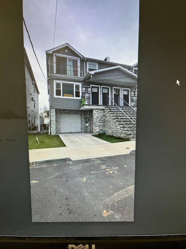 view of front of property featuring a balcony, stone siding, and a garage